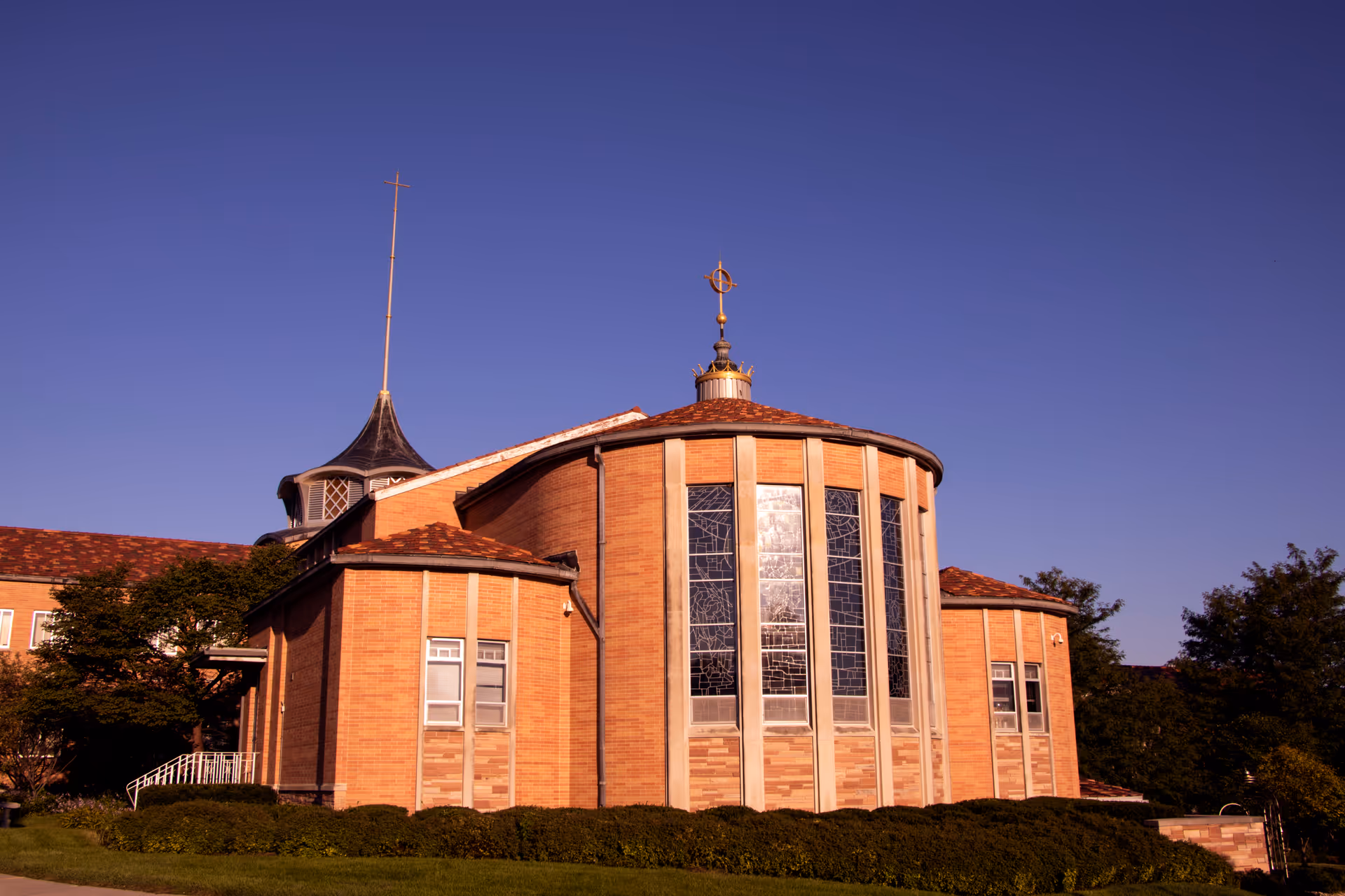 Brick retirement center exterior with curved glass windows against a blue sky.