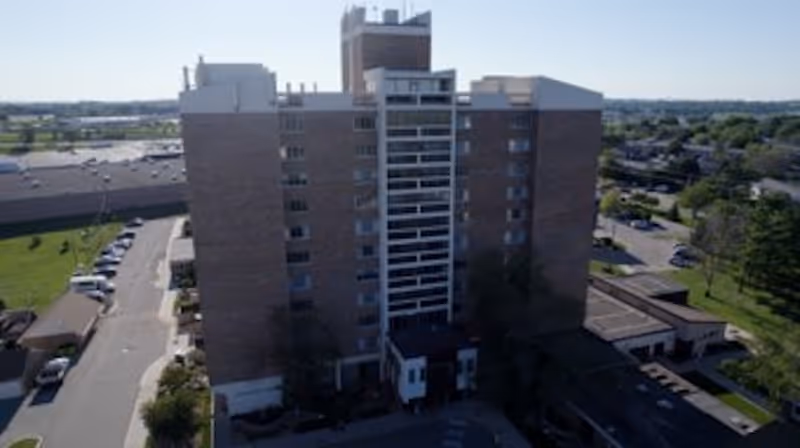 Aerial view of Madonna Towers of Rochester, a brick multi-story senior living building.