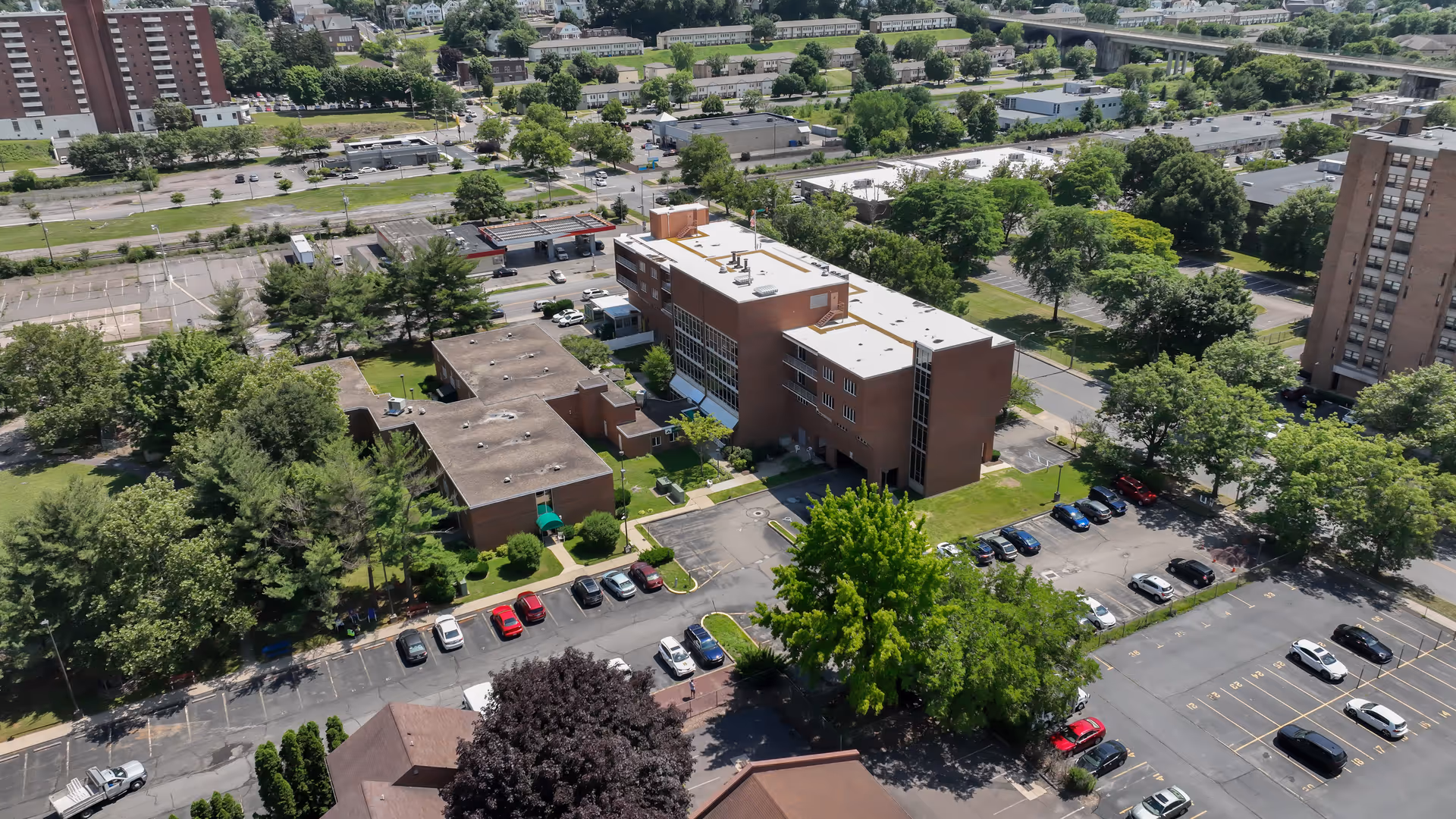 Aerial view of a brick senior living campus with parking lots and trees.