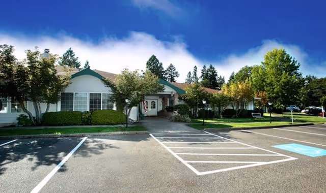 Exterior view of Fox Hollow senior living facility with parking and trees.