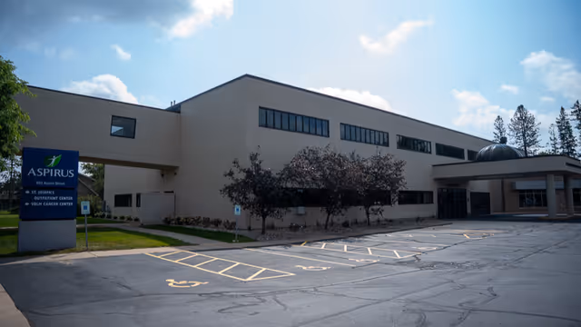 Exterior view of Aspirus building with parking area and landscaped trees.