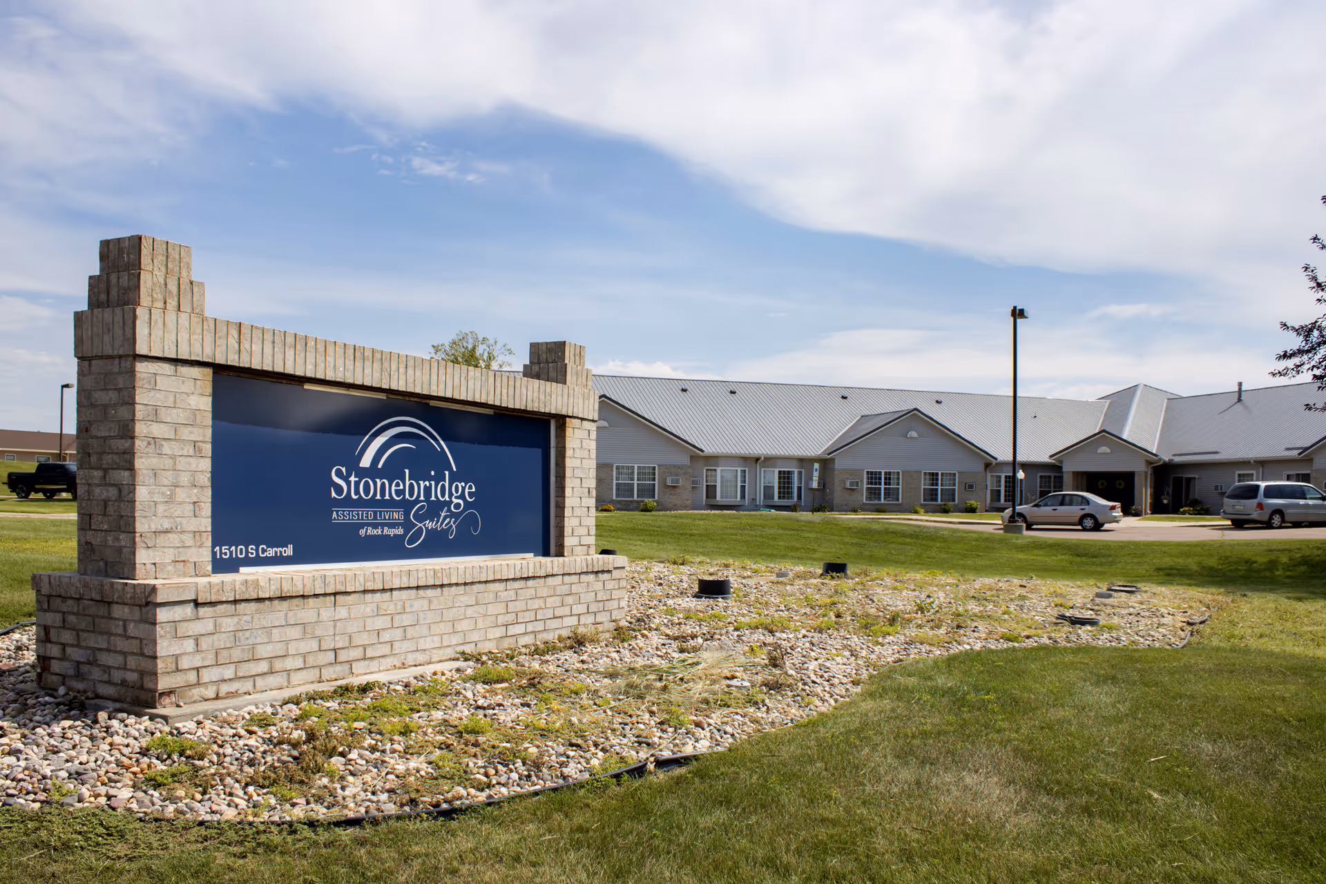 Stonebridge Assisted Living sign in front of a single-story facility with parked cars.