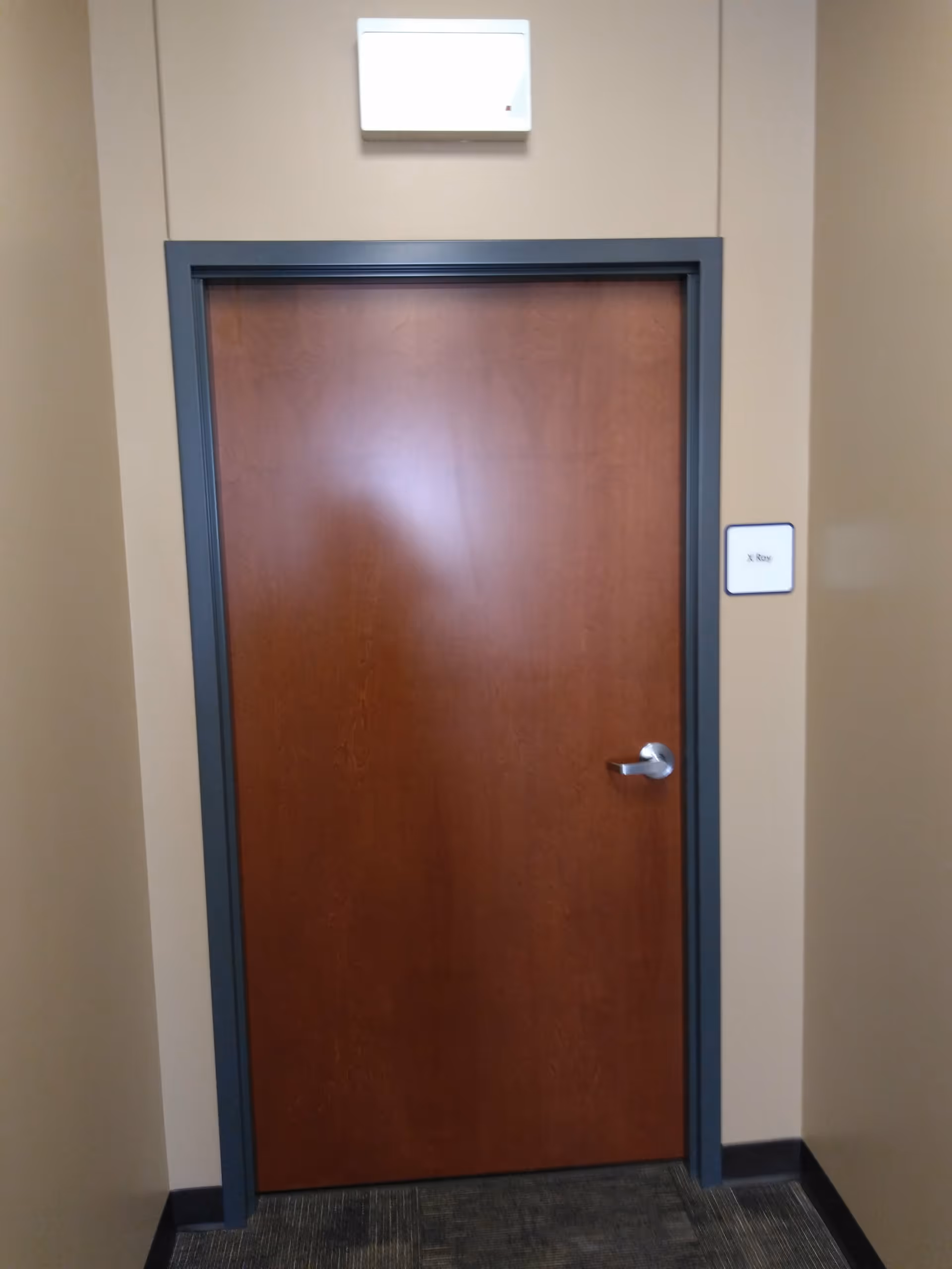 Interior hallway with a wooden door framed in blue-gray under a wall light.