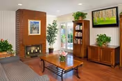 Cozy living room at Norwalk Meadows Nursing Center with fireplace, TV, bookshelves, and seating.