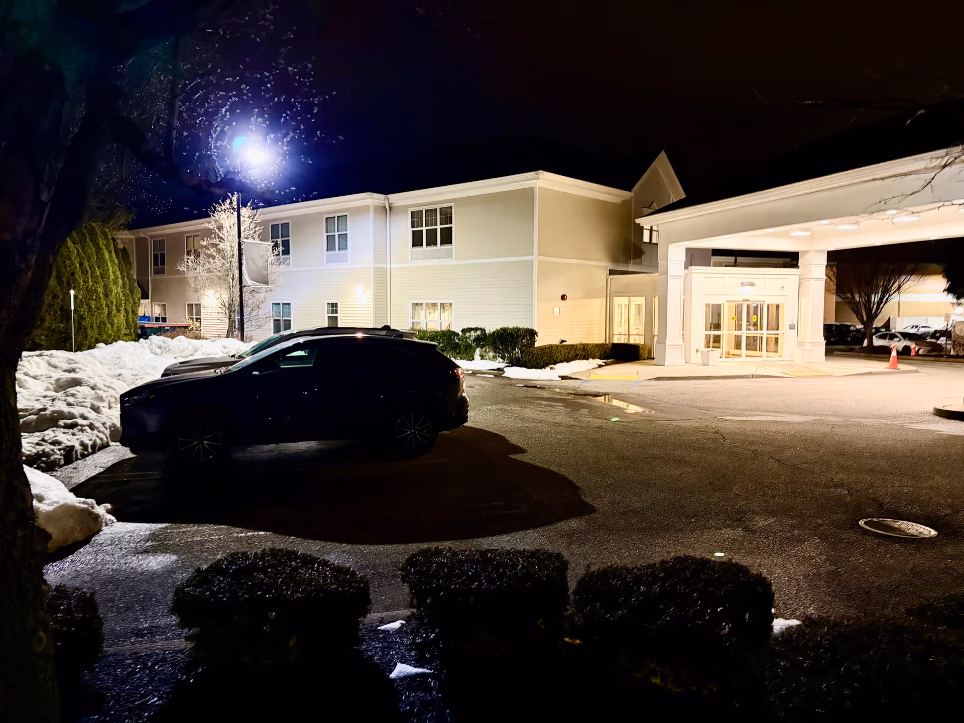 Nighttime exterior view of Belair Care Center with lit entrance and a parked car.