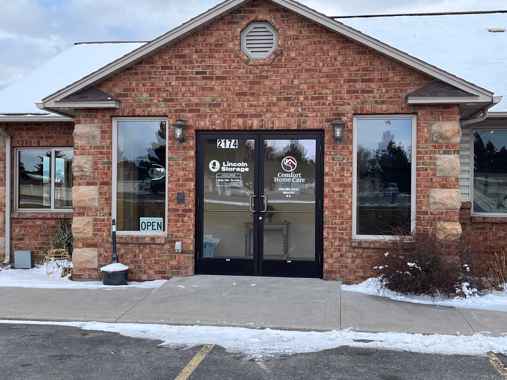 Brick facility entrance with glass doors and snow around, Comfort Home Care signage.