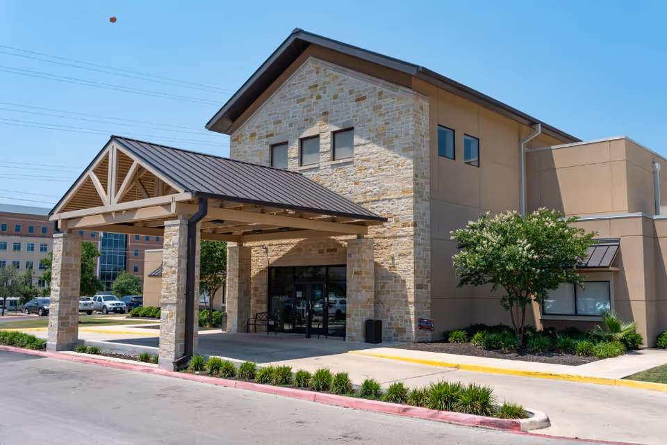 Exterior view of The Enclave senior living facility with stone facade and covered entrance.