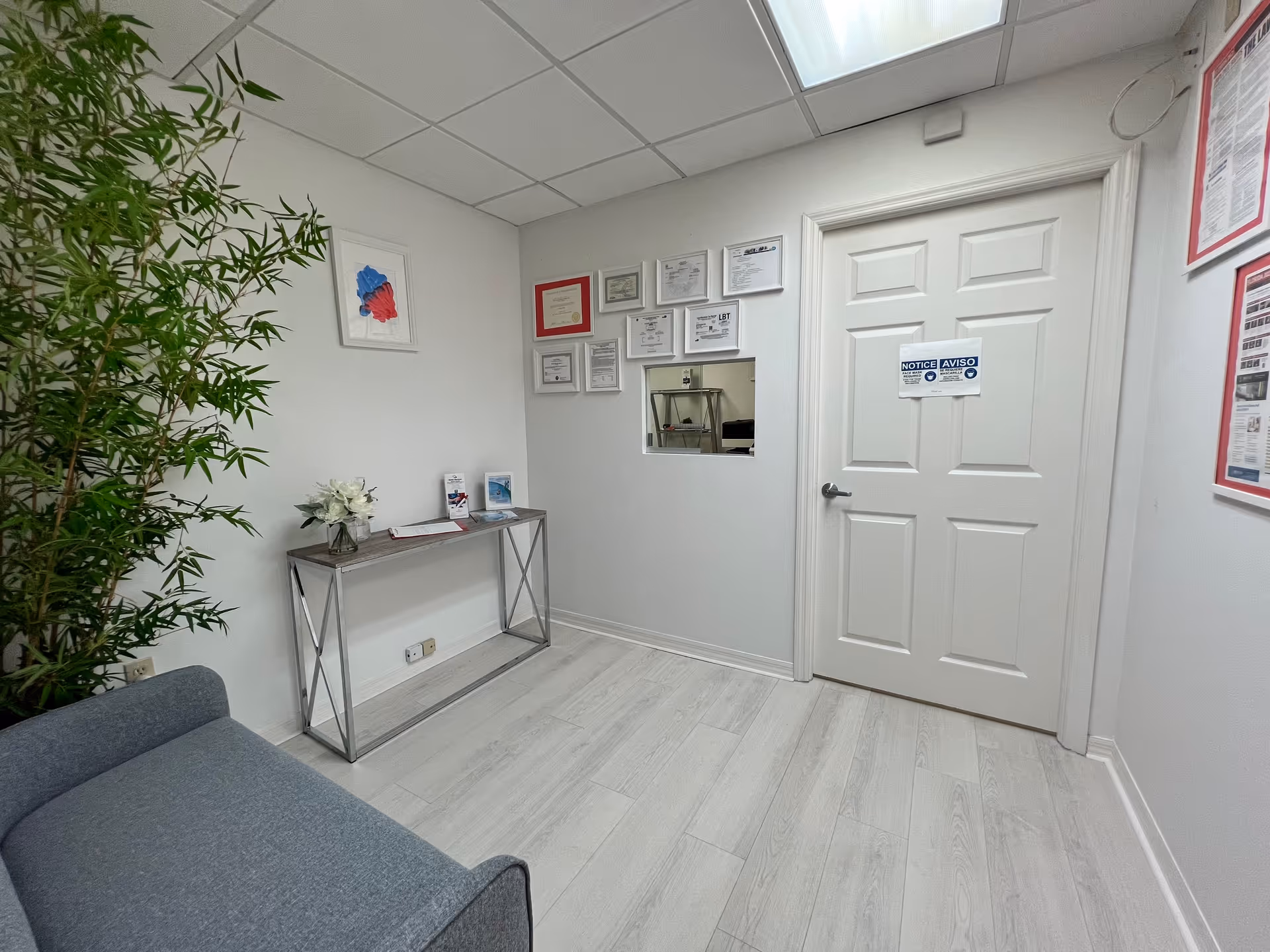 Bright interior hallway of a senior facility with a sofa, plant, and certificate wall.