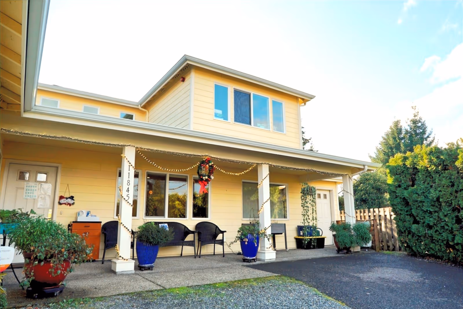Yellow senior living facility exterior with a covered front porch and string lights.
