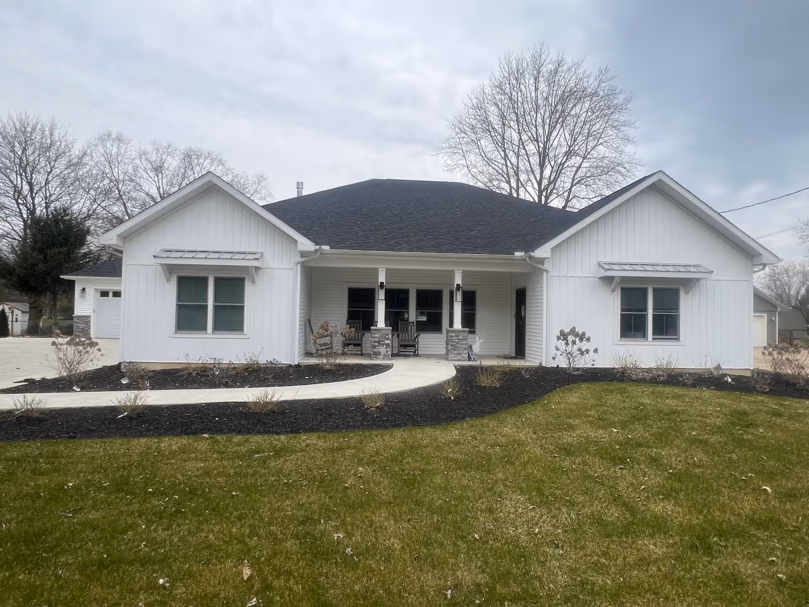 White single-story senior living building with a covered front porch and chairs.