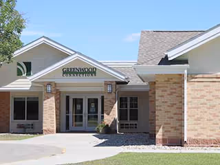 Front entrance of Greenwood Connections senior living facility, brick exterior with glass doors.