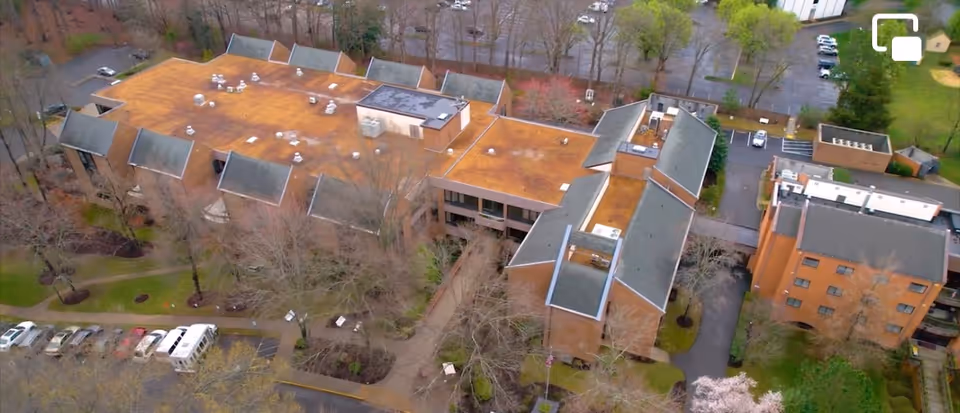 Aerial view of a multi-wing senior living facility with brown rooftops and surrounding parking.