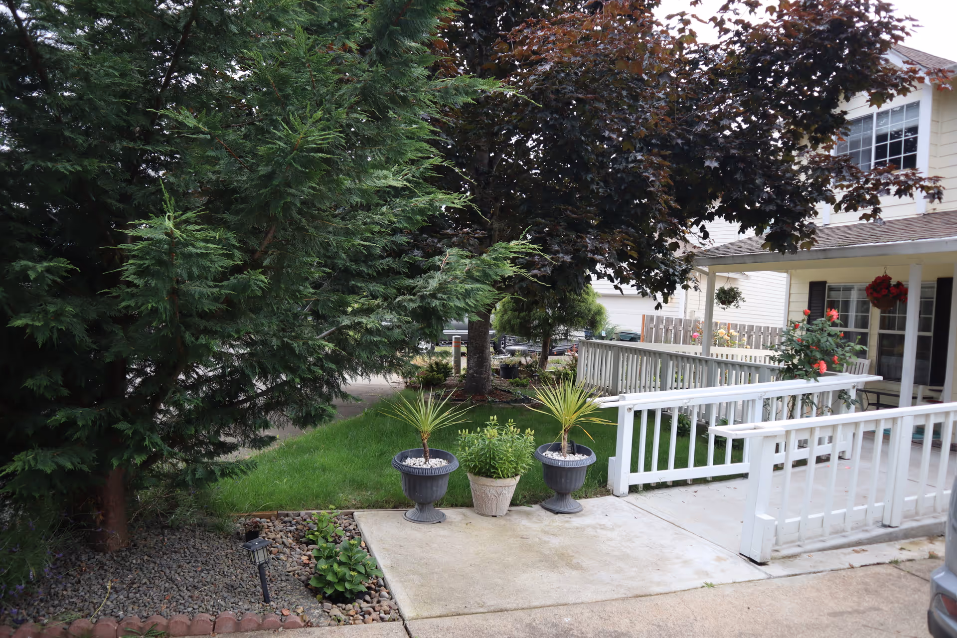 Front entrance of Unity Adult Foster Care with white railings and potted plants.