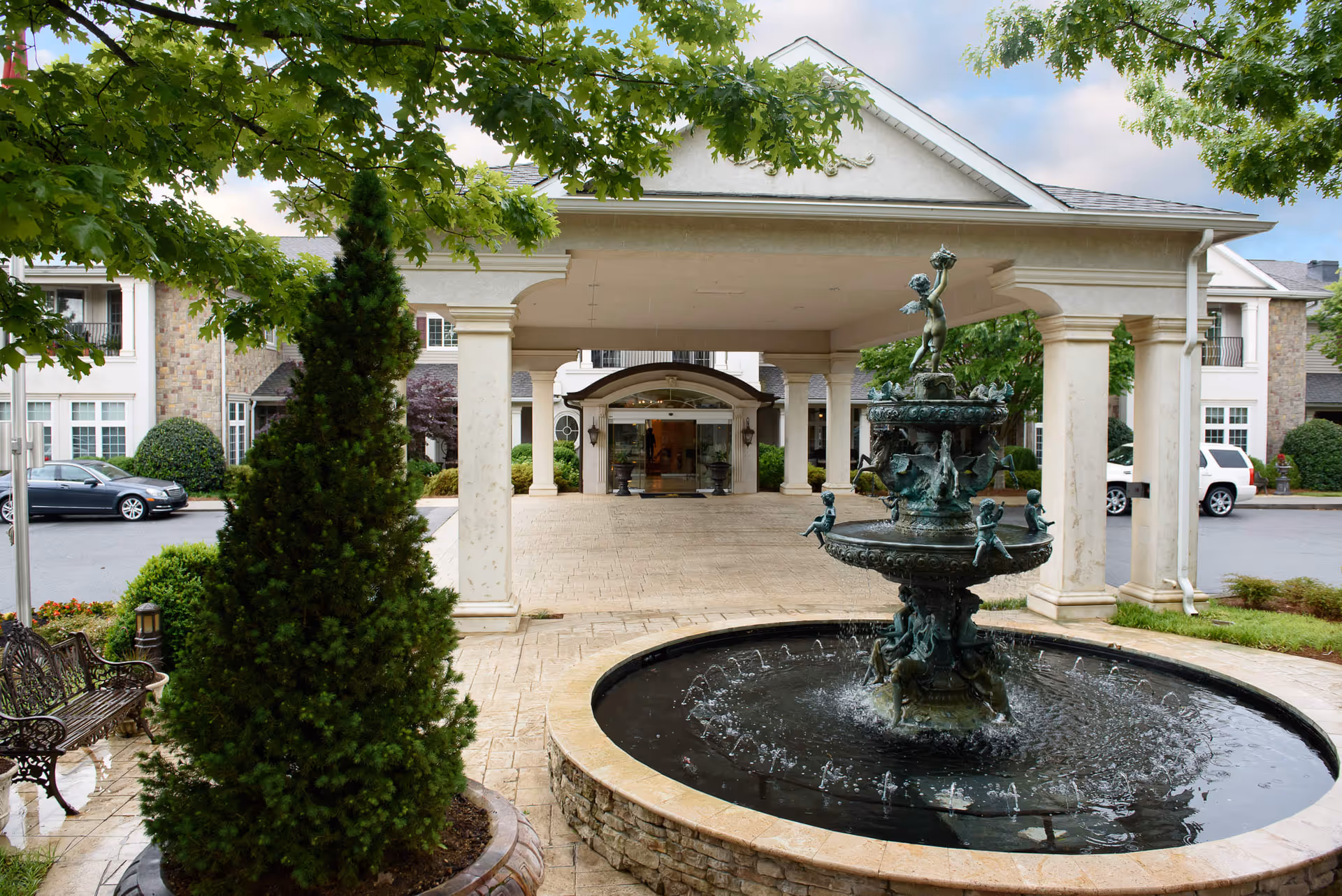 Front entrance with a covered porte-cochere and a decorative fountain in the driveway.