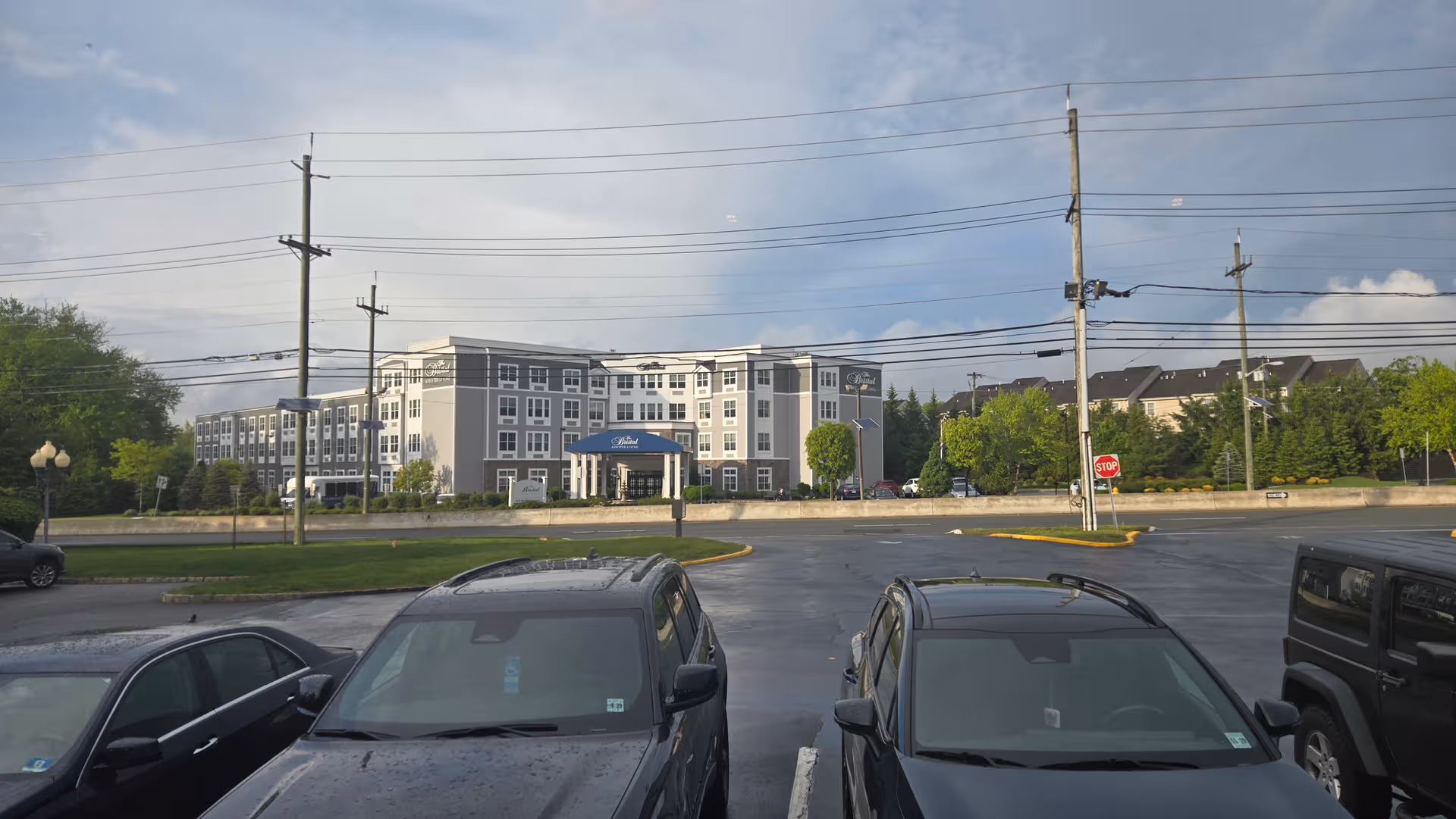 Exterior view of The Bristal Assisted Living at Wayne with a multi-story building and parked cars.
