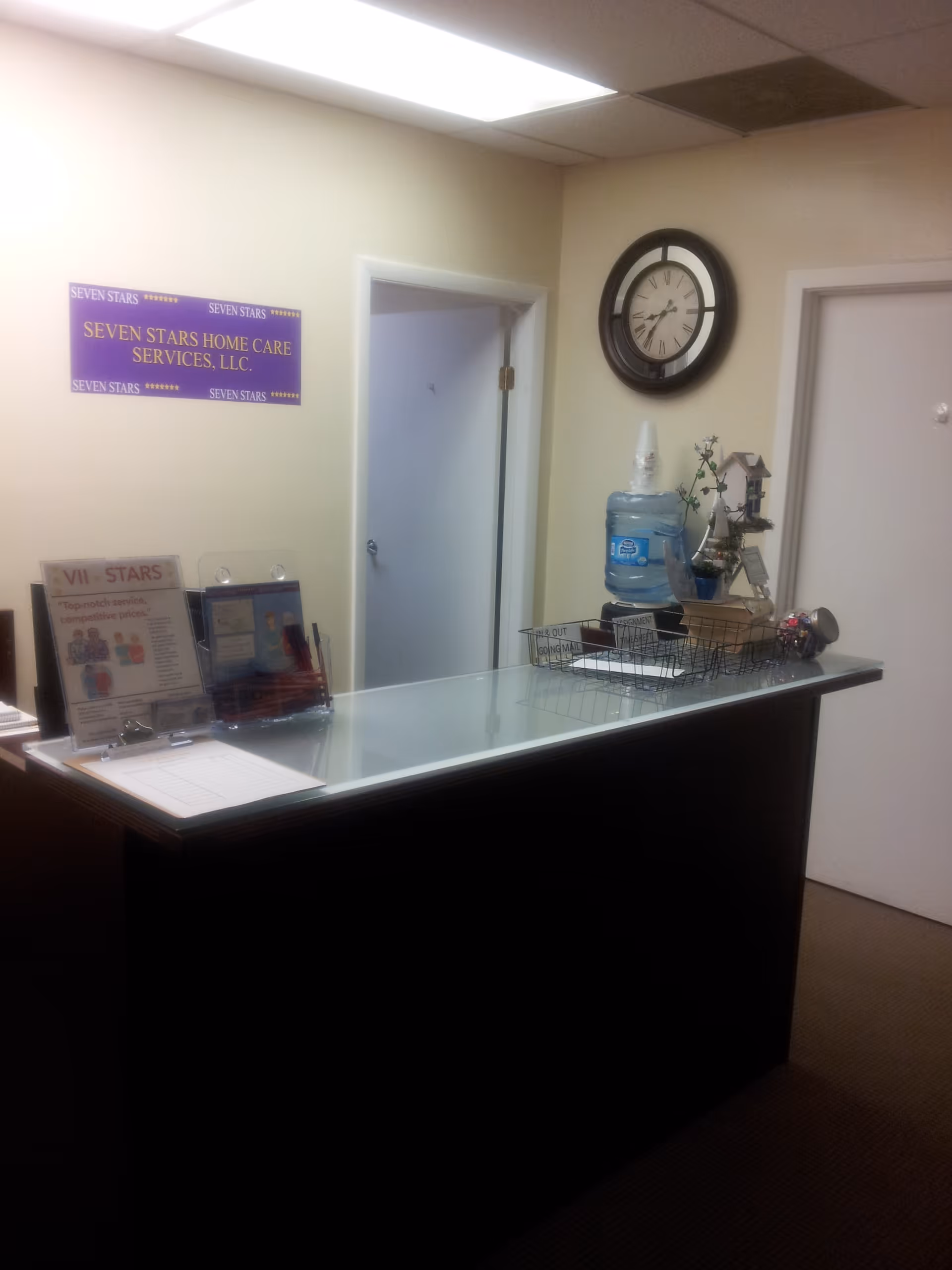 Reception desk in a lobby with wall sign, clock, and water cooler.