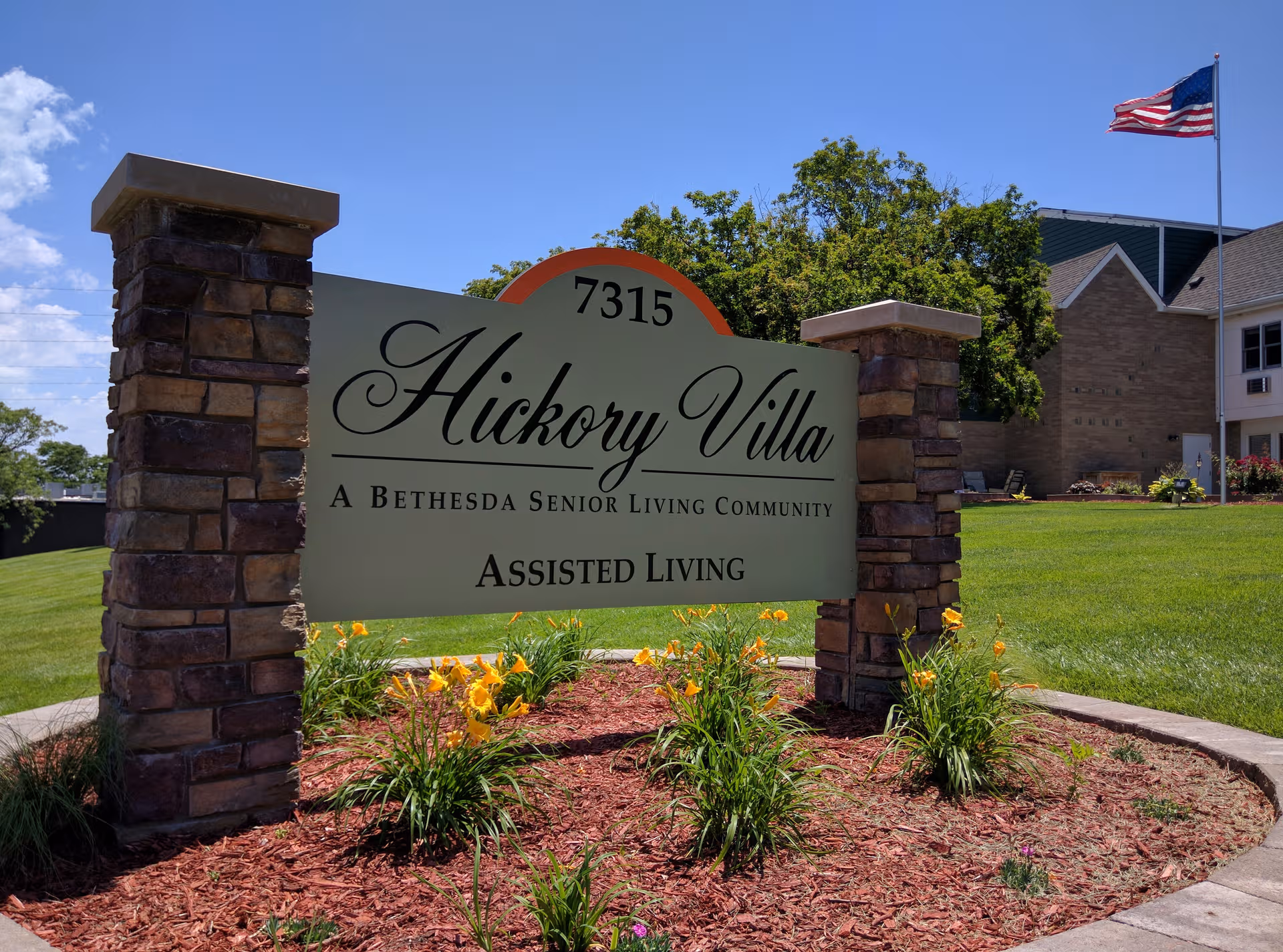 Sign reads Hickory Villa Assisted Living at entrance with landscaped flowers and building behind.