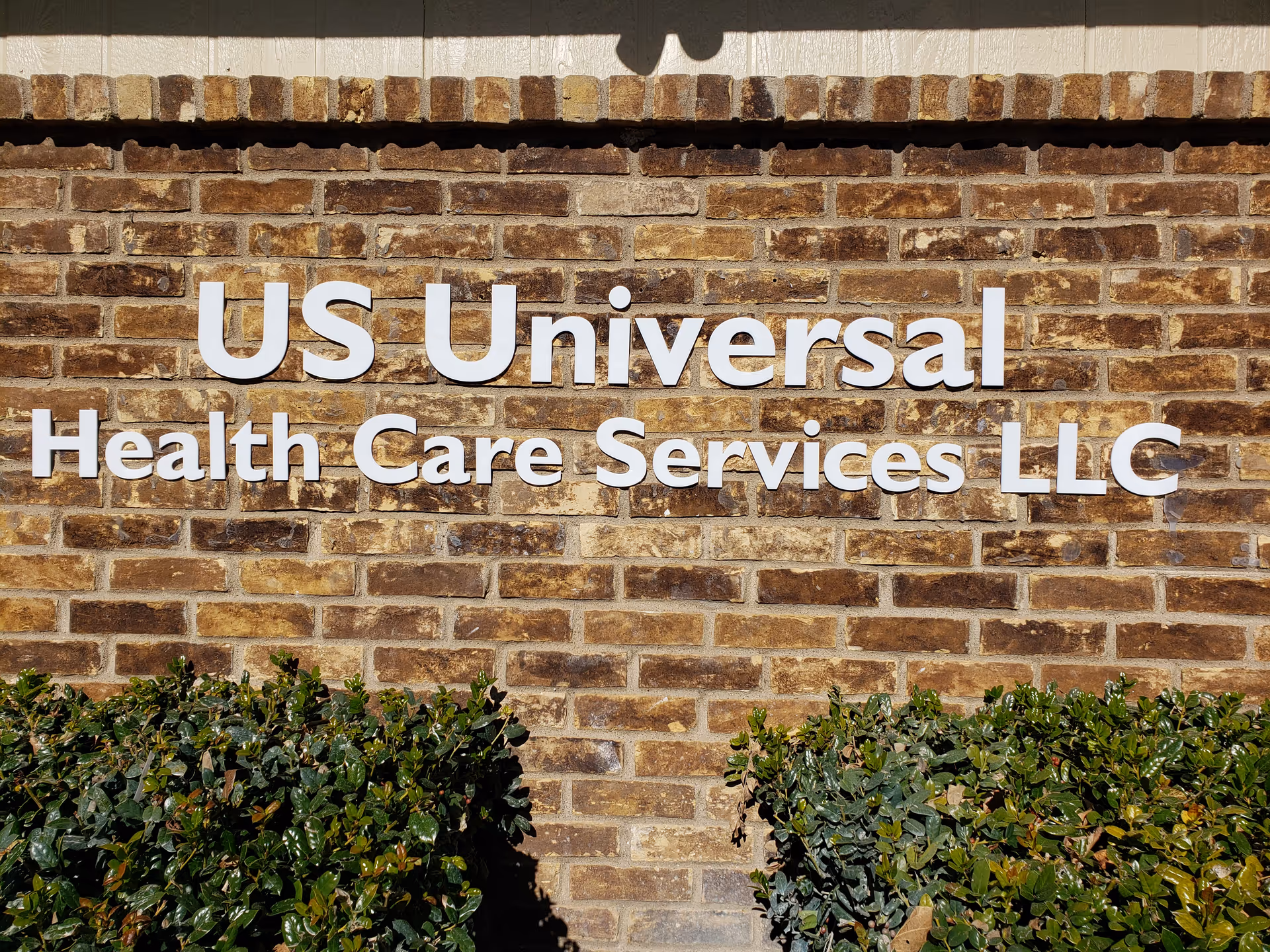 Brick wall features large white sign reading 'US Universal Health Care Services LLC'.