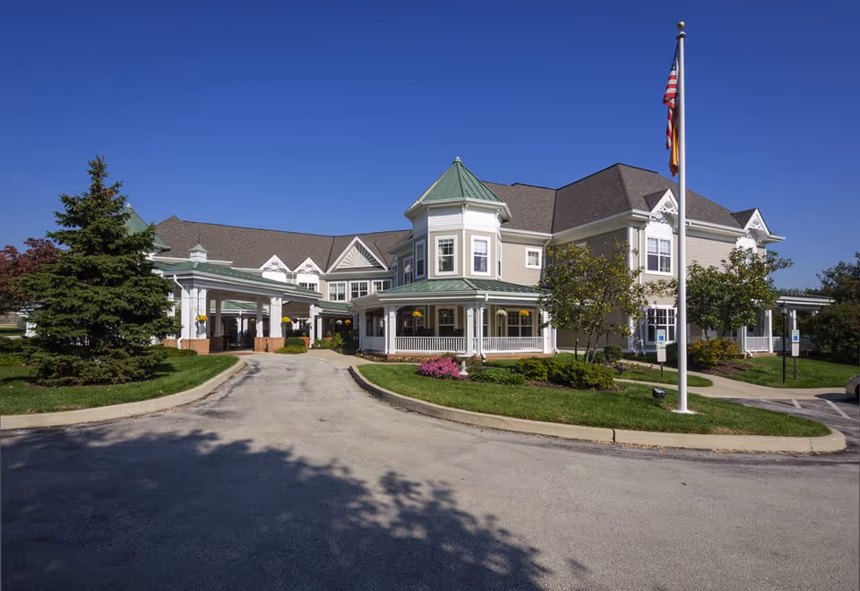 Sunny exterior view of Sunrise of Westtown facility, with entrance, flagpole, and landscaping.