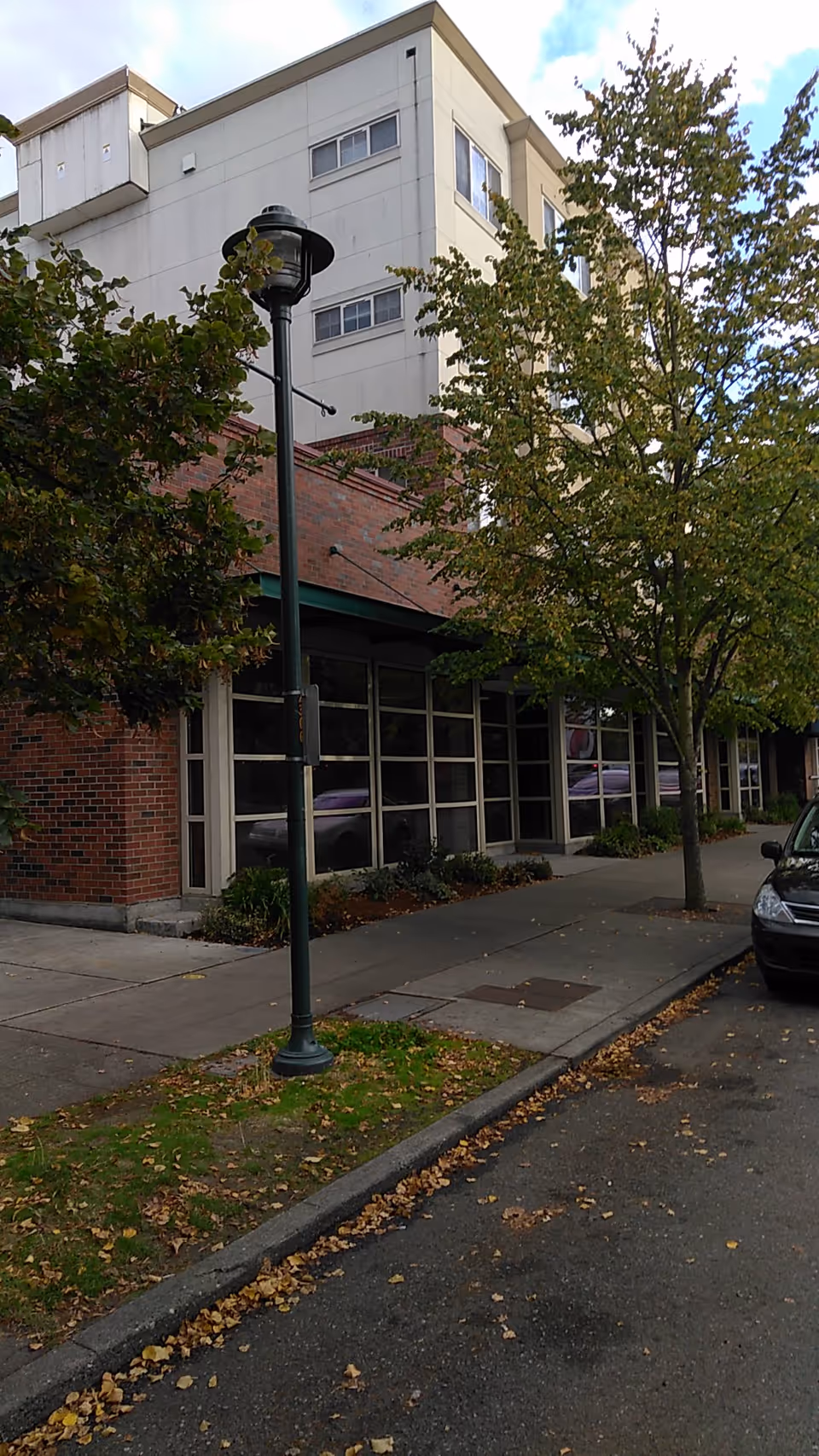 Exterior view of Brookdale Admiral Heights with trees, sidewalk, streetlamp, and glass-front entrance.