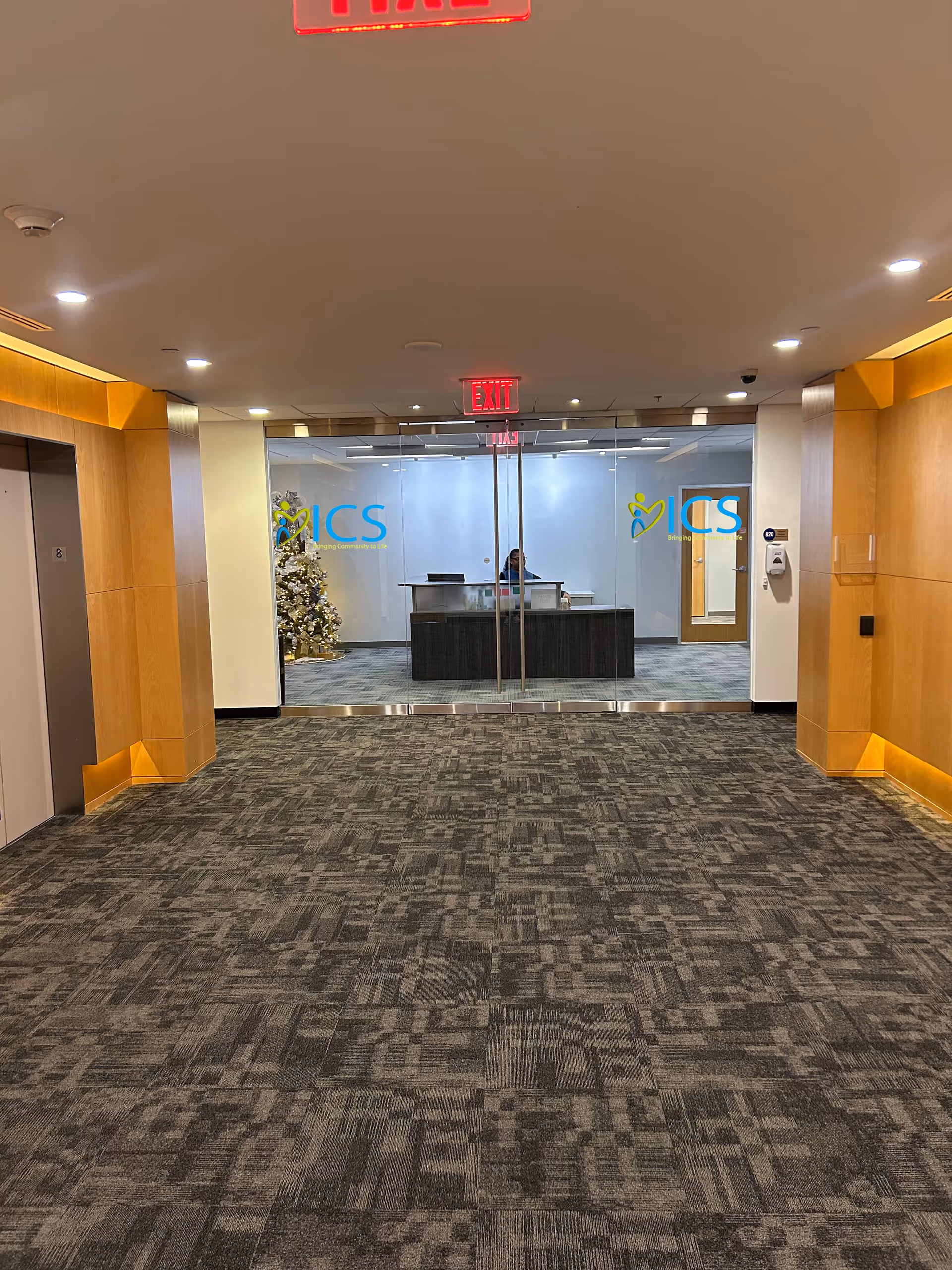 Hallway to glass-walled reception area with ICS logos and a receptionist desk.