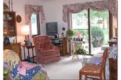 Cozy living room with pink armchair, TV, and sliding glass doors to an outdoor patio.
