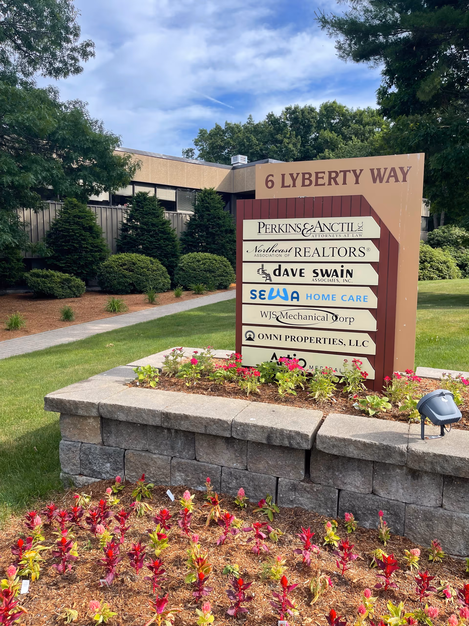 Outdoor sign listing SEWA Home Care among tenants at a building entrance with landscaping.