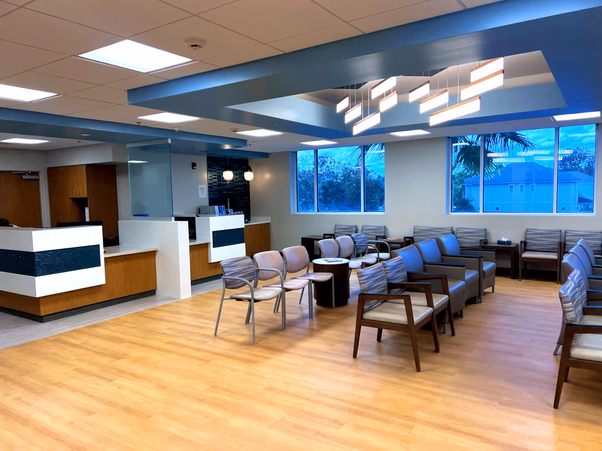 Bright interior waiting area with modern seating, a reception desk, and large windows.