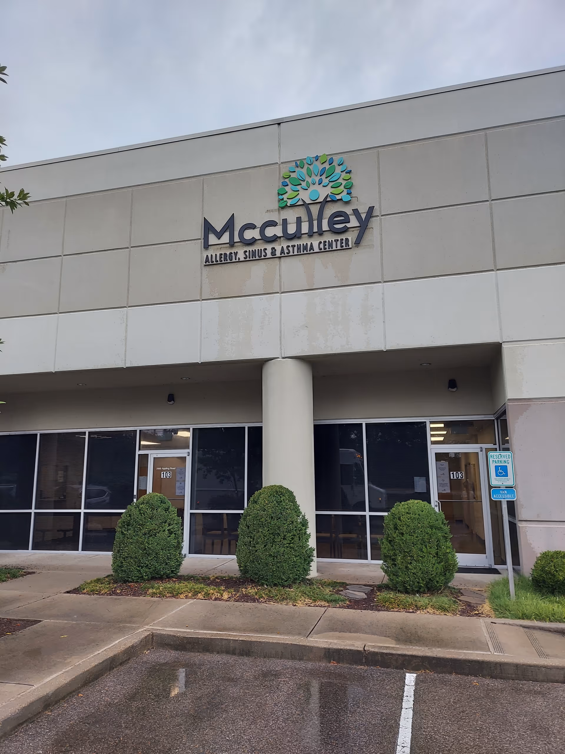 Exterior view of a medical center storefront with glass doors and shrubs