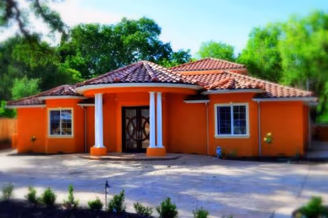 Orange stucco building with tiled roof and white columns at entrance.