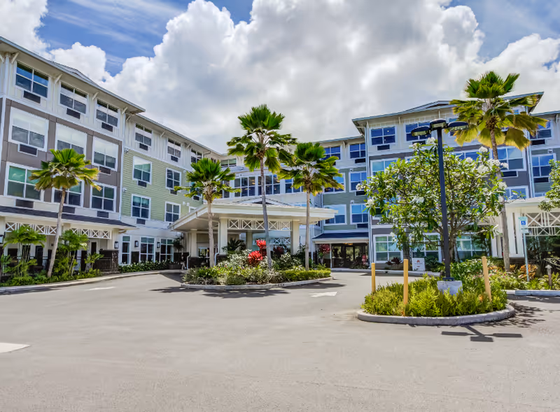 Exterior view of The Plaza at Kaneohe with palm trees and a driveway.