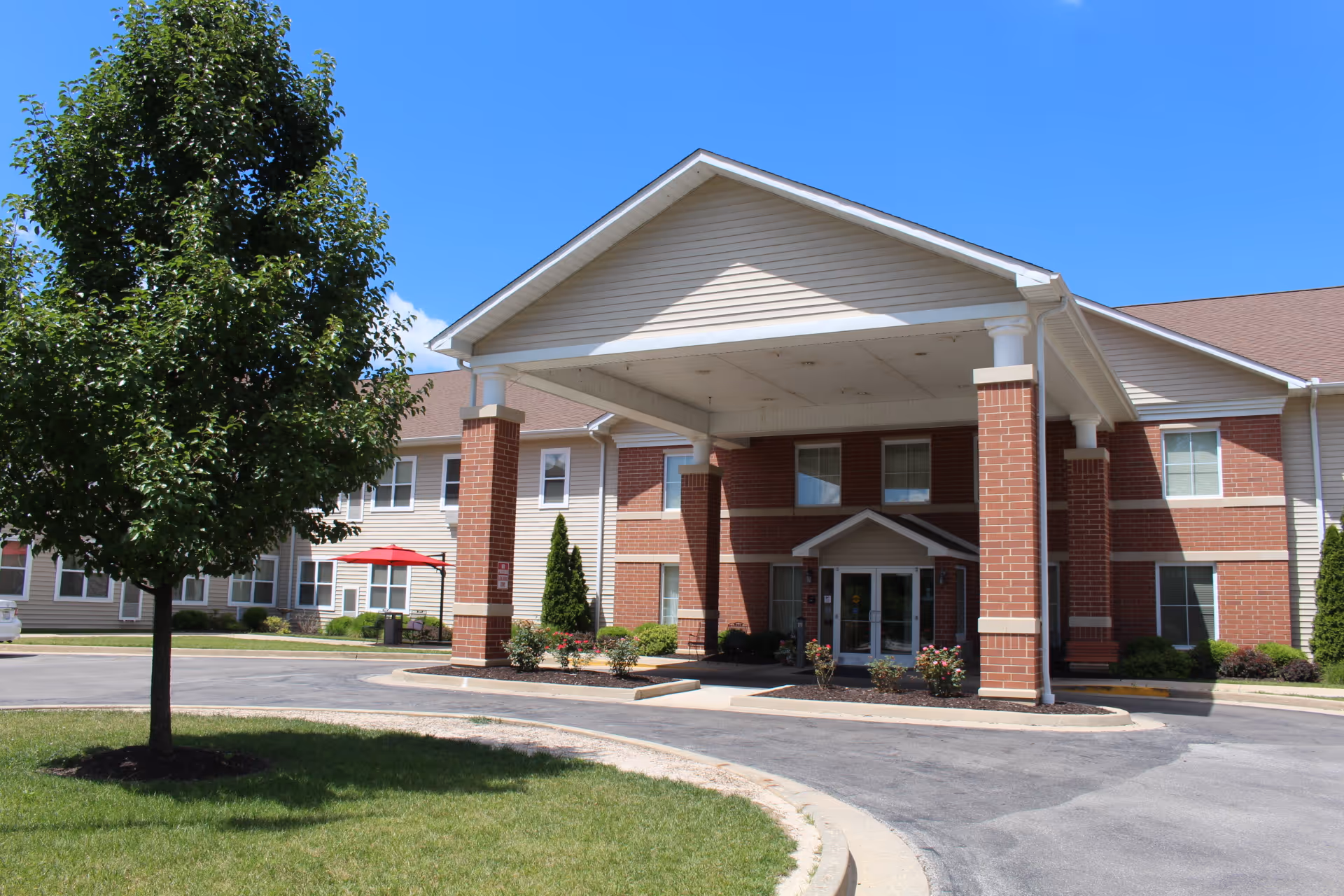 Front exterior of Evergreen Place Supportive Living Alton with brick entrance and porte-cochère.