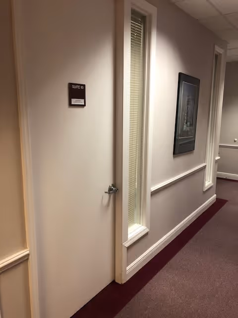 Narrow hallway with a closed suite door labeled Suite 10 and framed wall art.