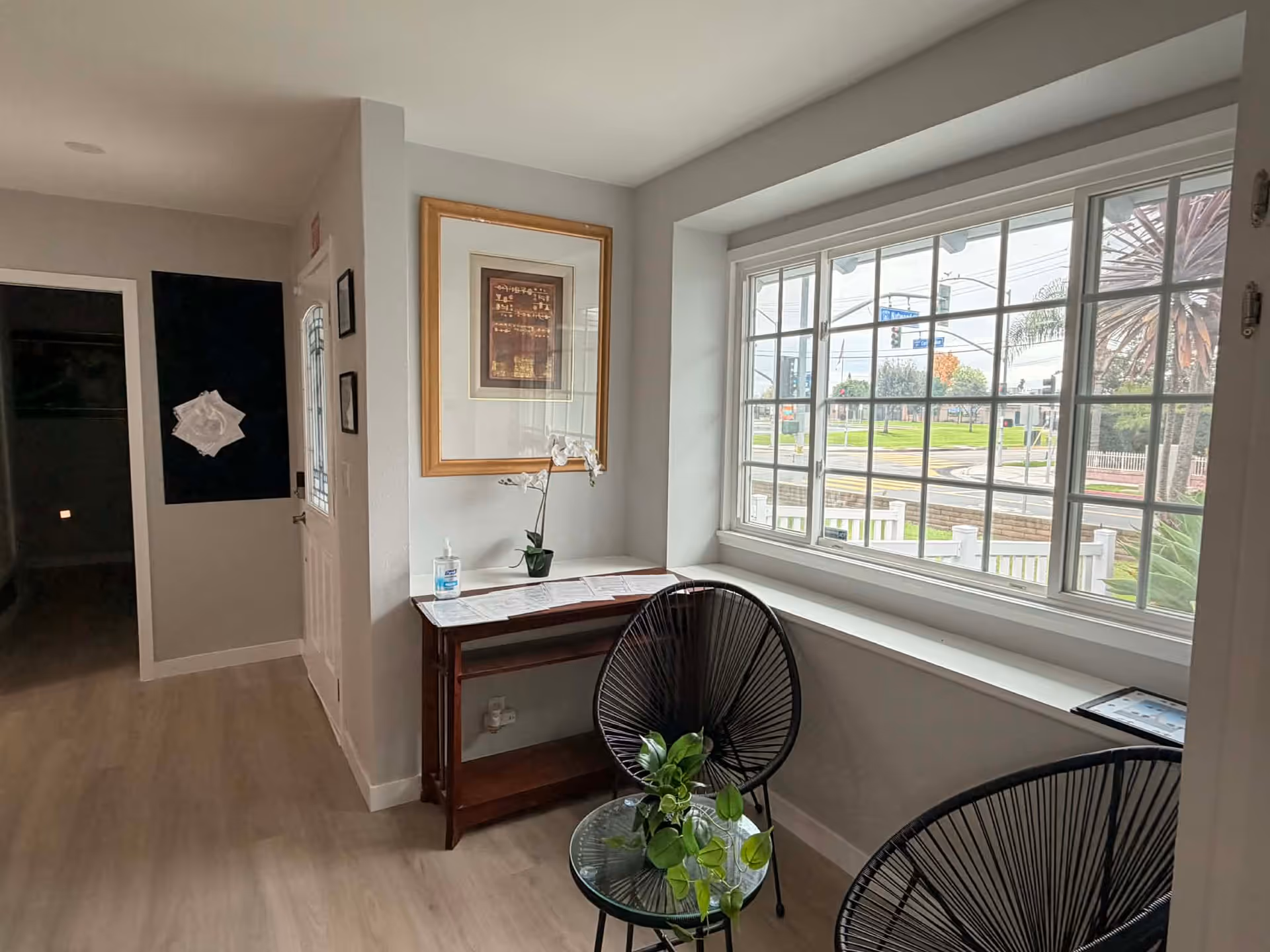Bright interior corner with a window, two black chairs, and a small table.