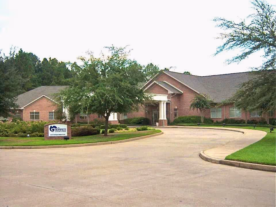 Brick hospice facility exterior with a curved driveway and manicured landscaping.