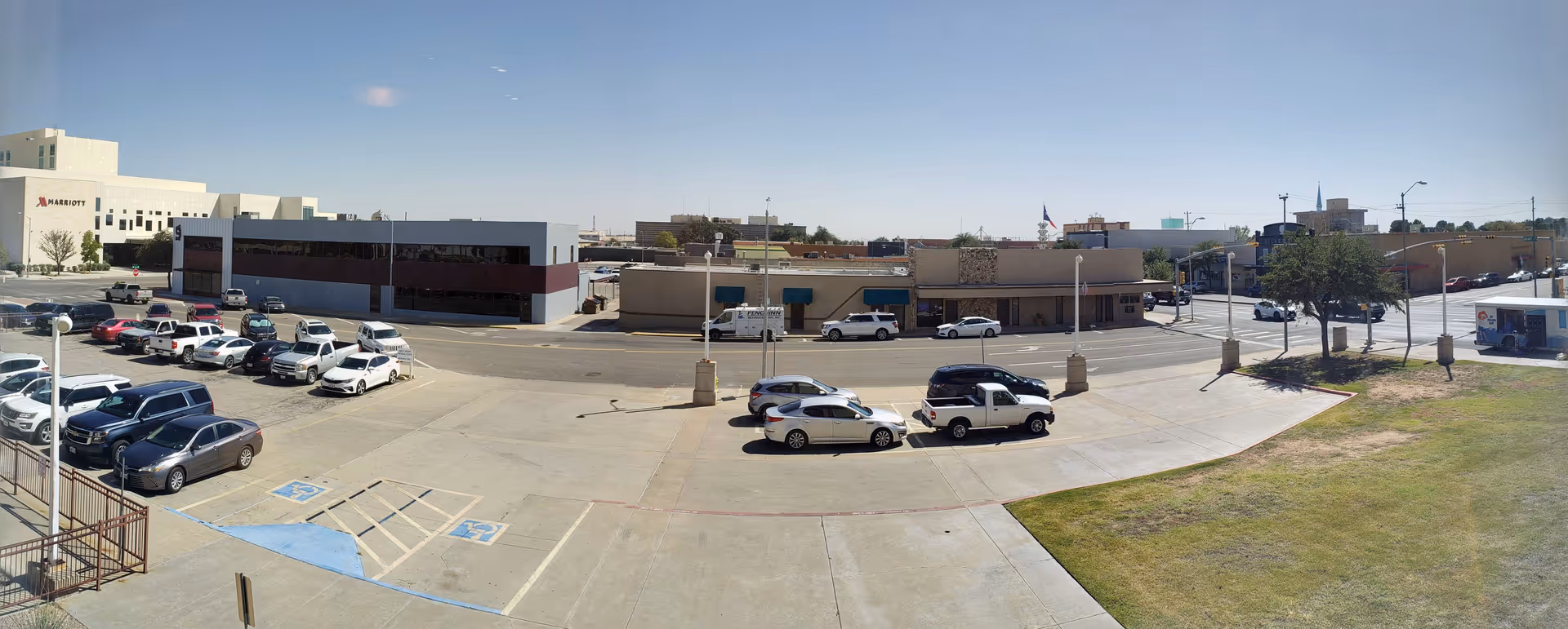 Wide exterior view of a parking lot and low-rise buildings under a clear blue sky.
