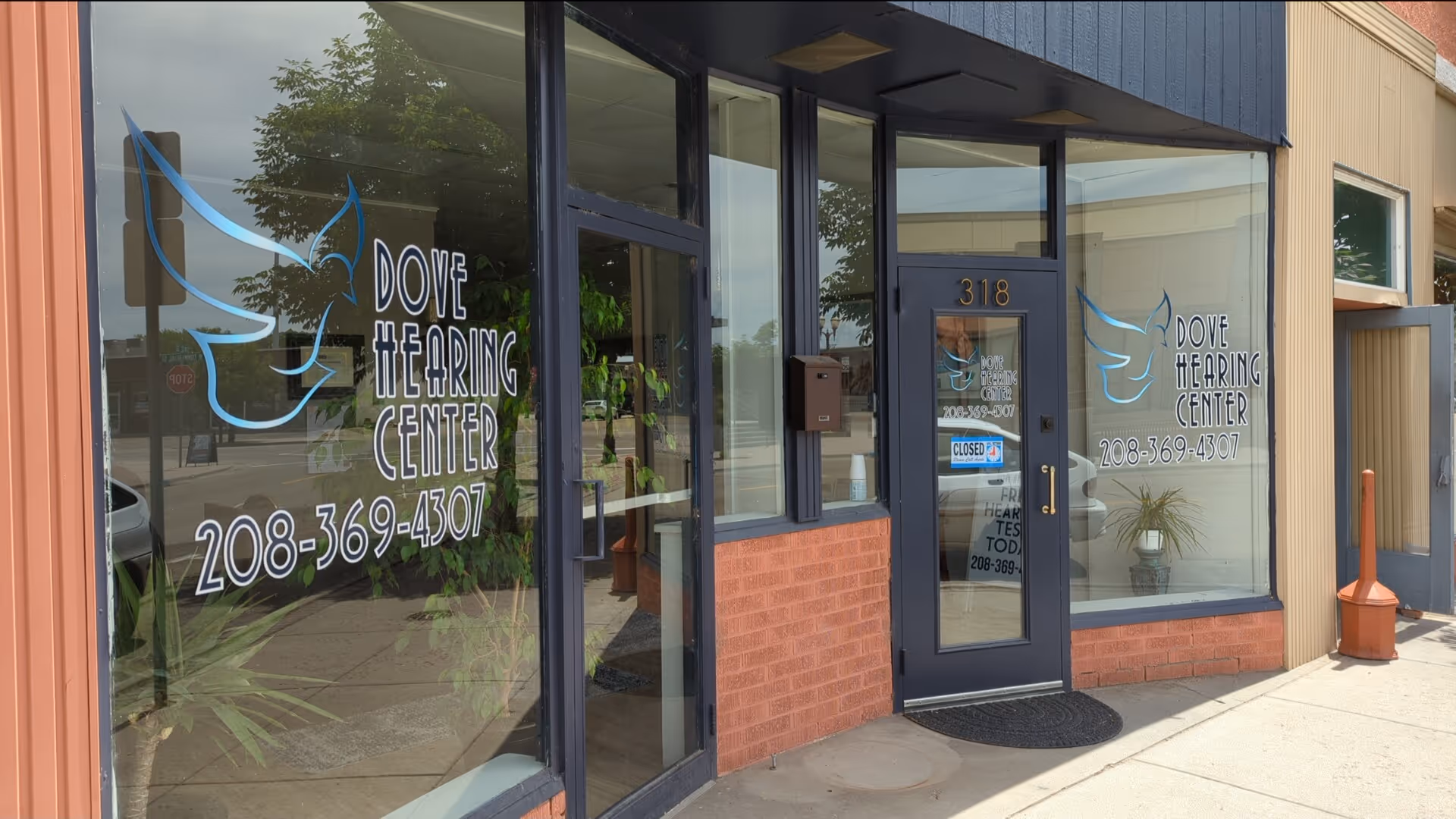 Storefront of Dove Hearing Center with glass windows, door, and contact numbers.