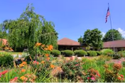 Front view of Chatuge Regional Nursing Home with a flower garden and flag.