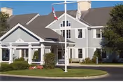 Exterior view of Harbor House Rehabilitation & Nursing Center with flagpoles and manicured landscaping.
