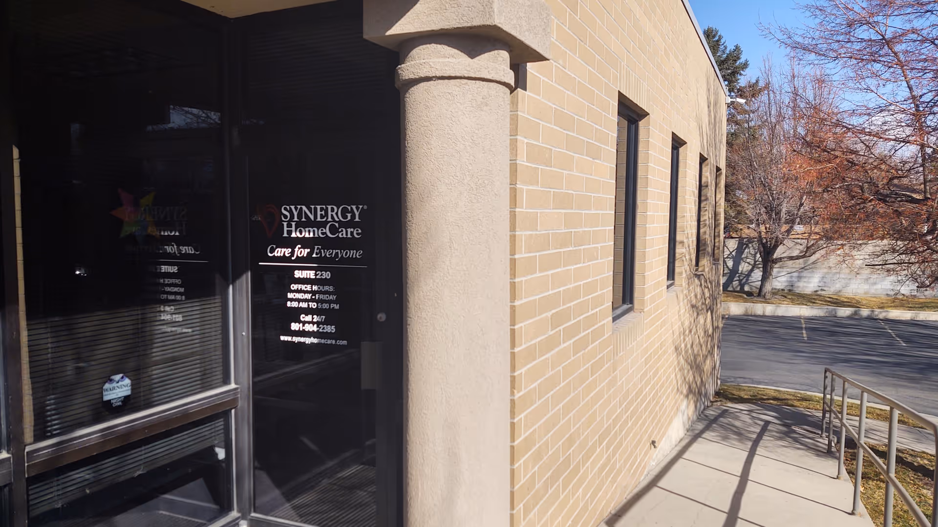 Exterior view of SYNERGY HomeCare entrance with brick wall and ramp.