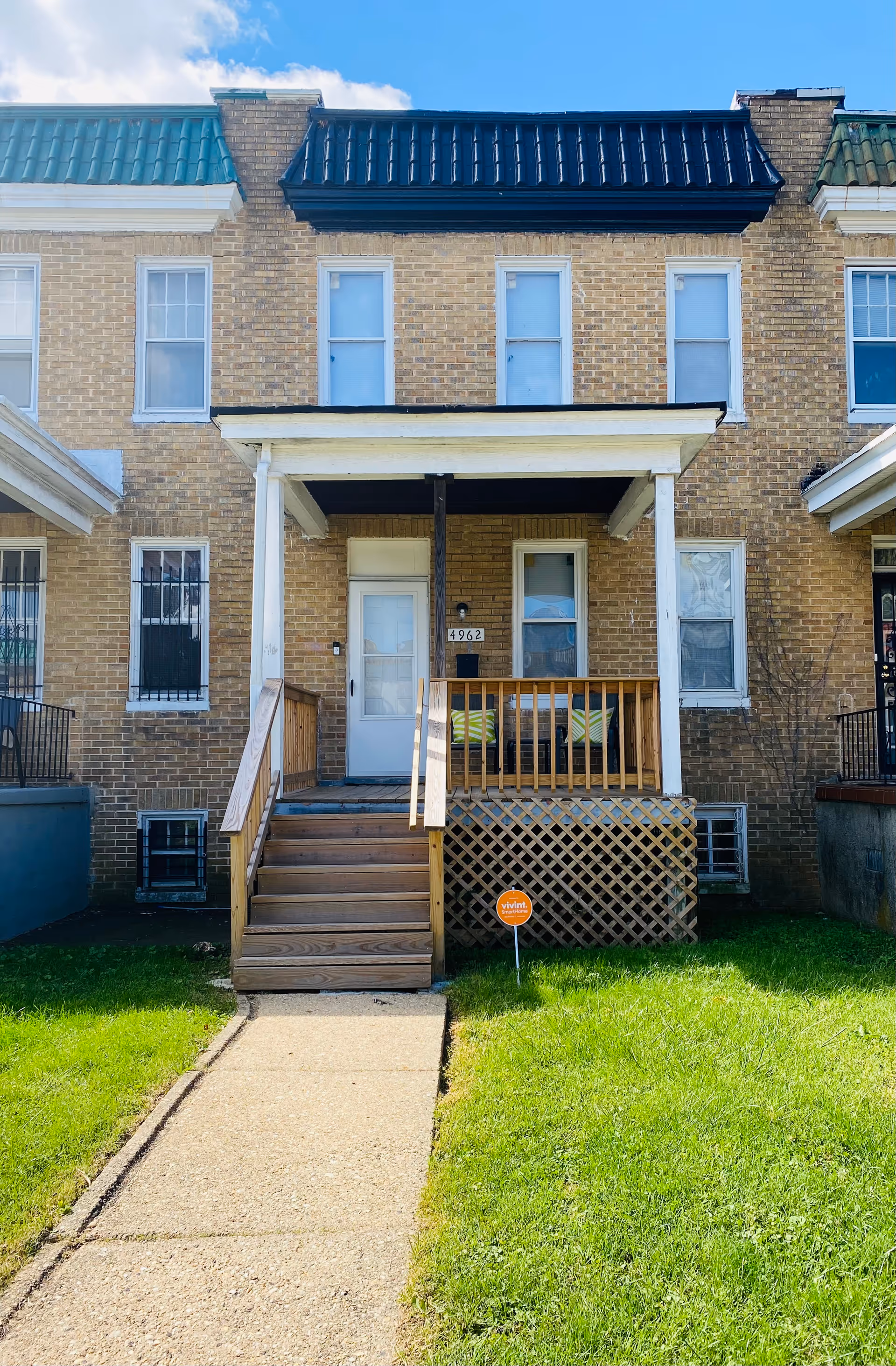 Brick residential building exterior featuring a front porch with stairs and railing.
