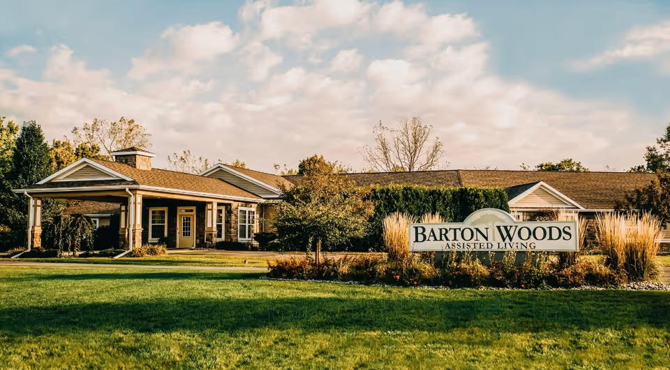 Front view of Barton Woods Assisted Living building with manicured lawn and sign.