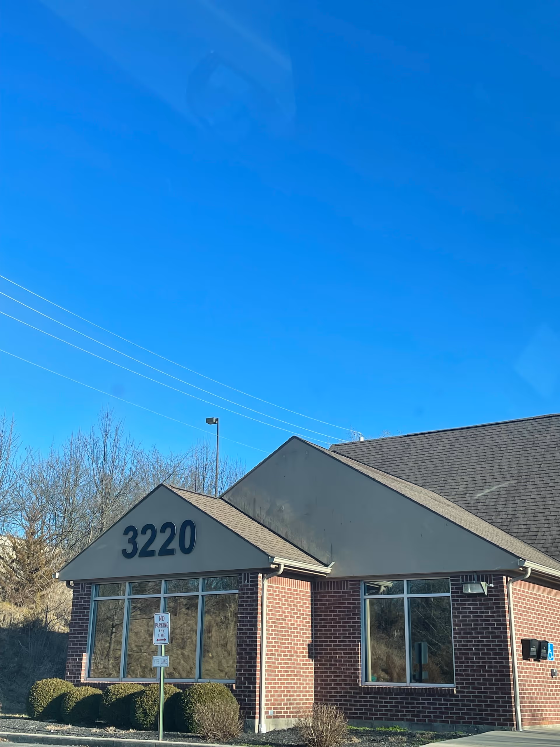 Brick building with address 3220 under a clear blue daytime sky.