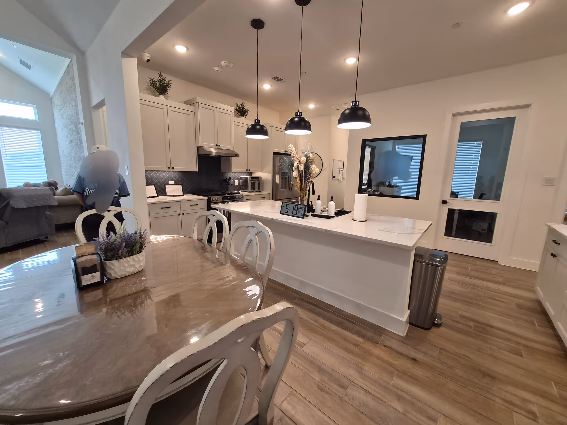 Modern kitchen with island, dining table, white cabinetry, and stainless appliances in a senior living facility.