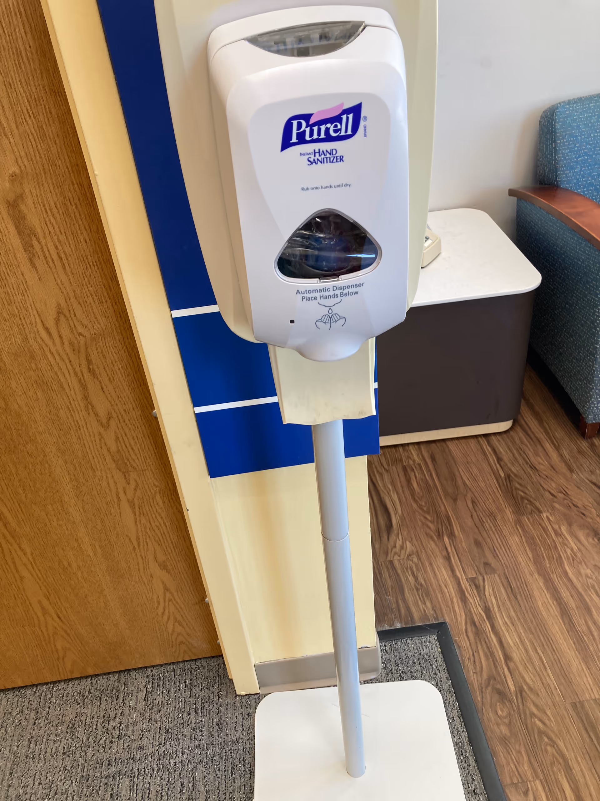 Purell hand sanitizer dispenser on a tall stand in a hallway.