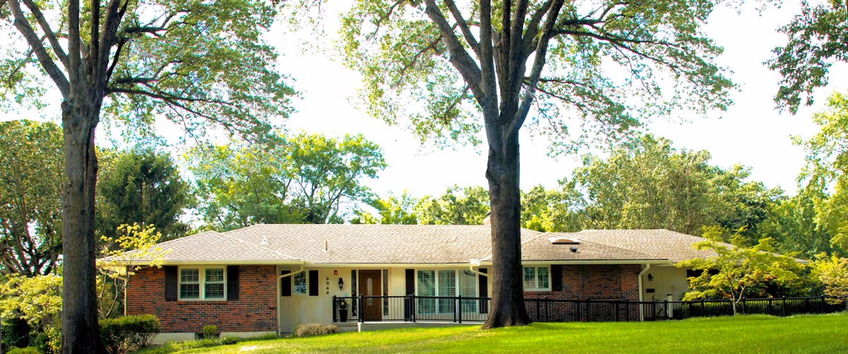 A single-story brick senior living facility with a front entrance and surrounding trees