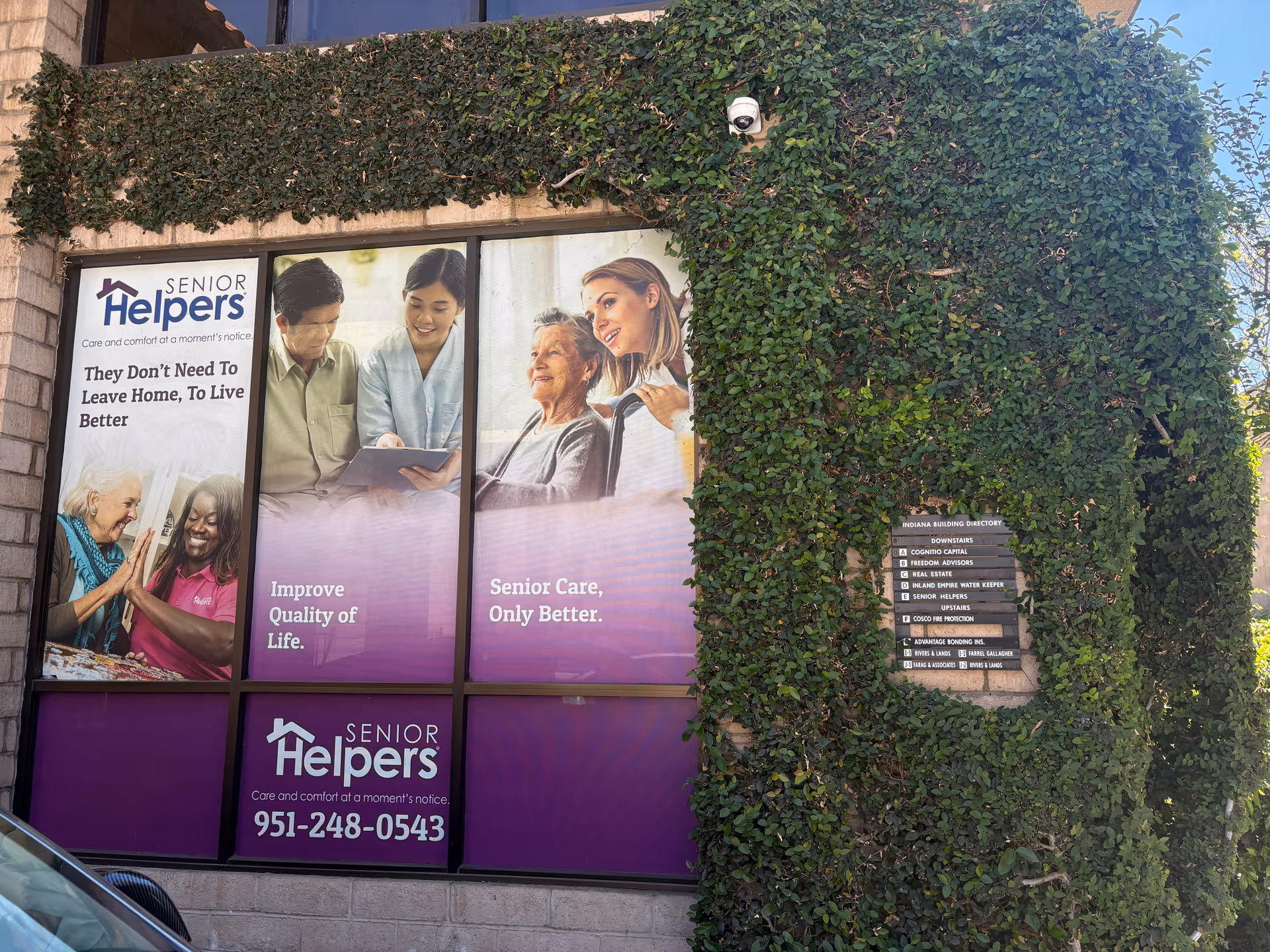 Front exterior of Senior Helpers facility with large window posters and ivy on the wall.