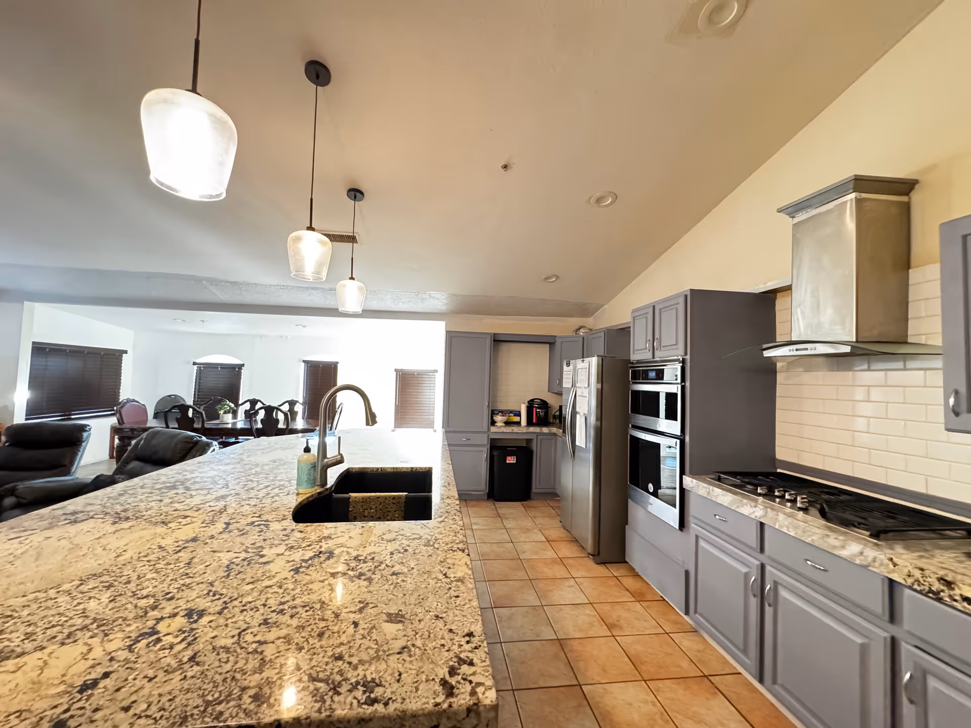 Large granite kitchen island with a sink and stainless steel appliances in a senior living facility.