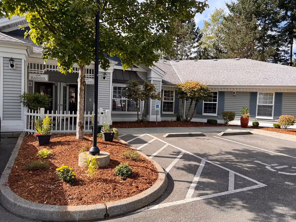 Front exterior of a senior living facility with parking and landscaped island.