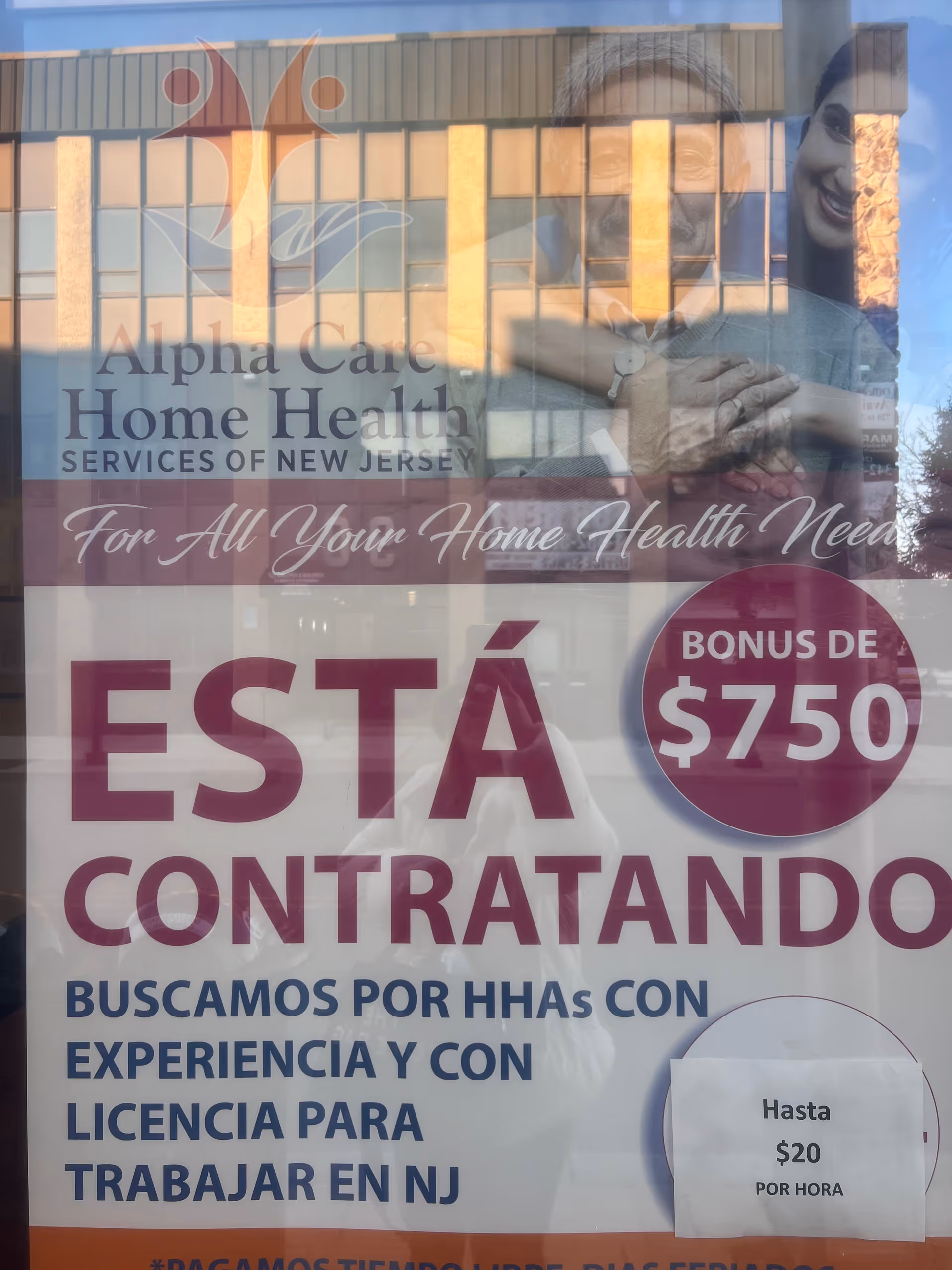 Glass storefront window for Alpha Care Home Health with large 'ESTÁ CONTRATANDO' sign and reflections.